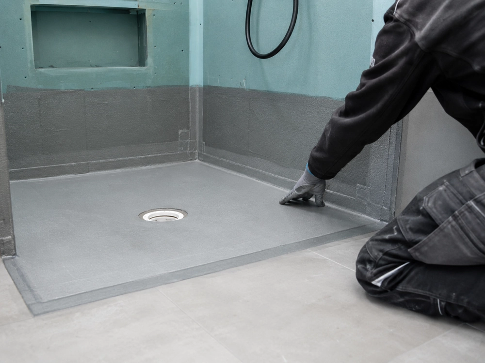 Montør udstrækker vandtætningsmembran i bruseniche ved renovering af badeværelse