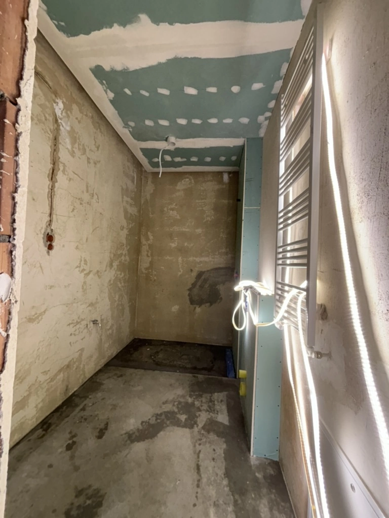 Badeværelse under renovering med betonvægge, vådrumsgipsloft og monteret radiator – renovering af badeværelse