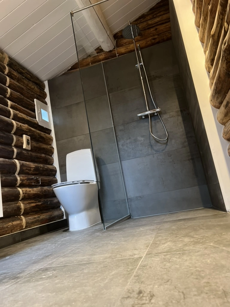 Fliser badeværelse med grå store fliser, glasafskærmning, regnbruser og toilet